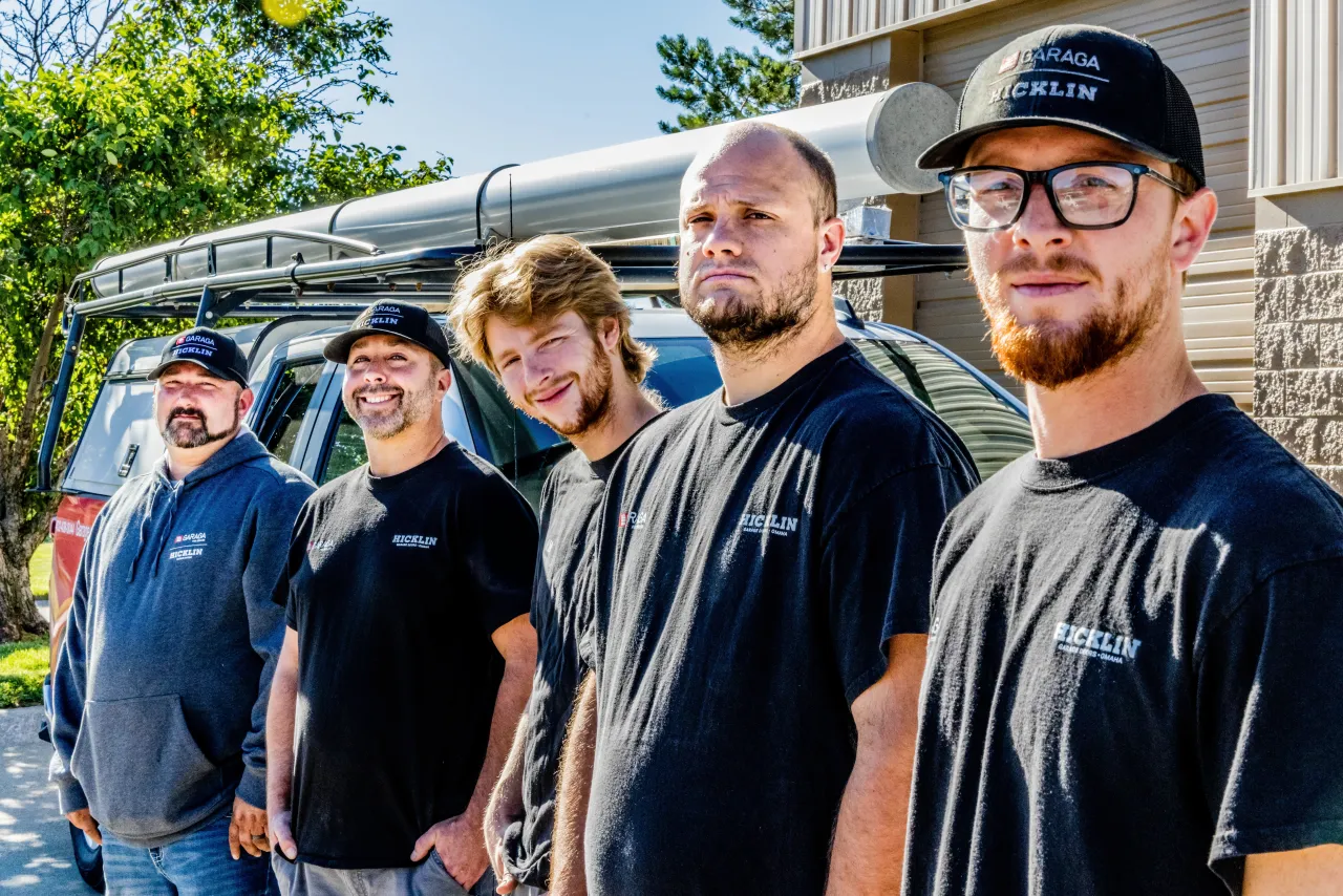 Garage door specialist in a row outside in front of a garage door service truck